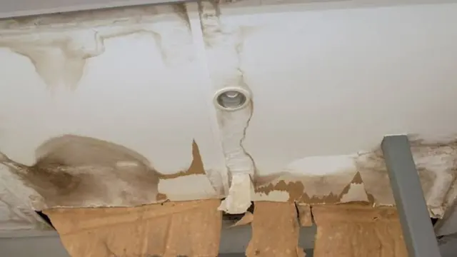 Brown water stain and peeling ceiling around a light fixture