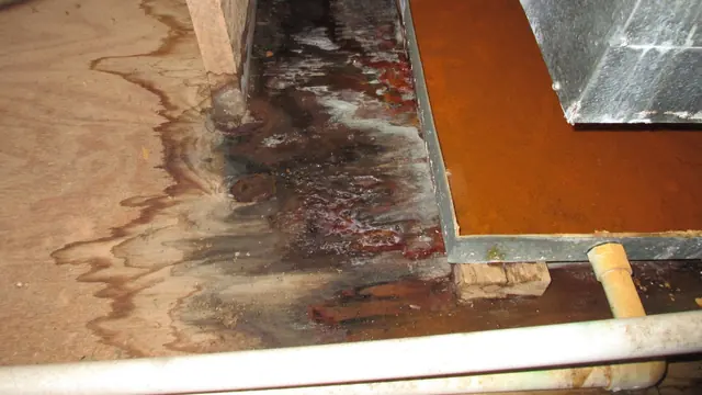 Water-stained wood subfloor next to a cut metal panel