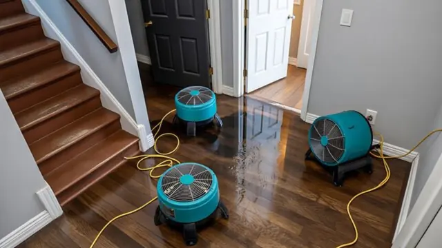 Two air movers drying a glossy wood floor beside a staircase